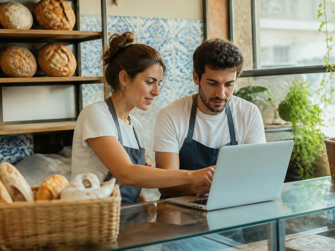 Dois sócios de uma padaria a preencher a página da empresa num portátil